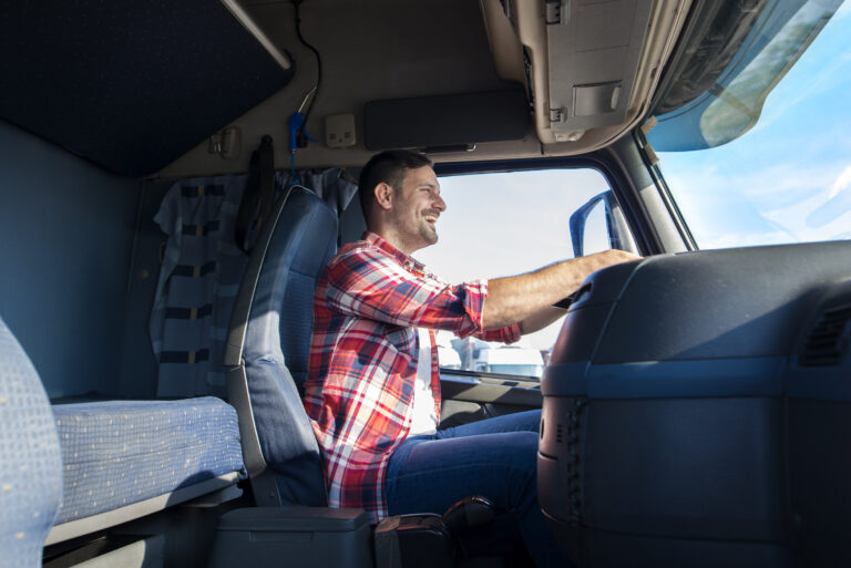 Professional middle aged trucker driving truck to the destination.